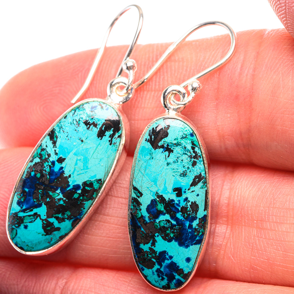 Shattuckite oval drop earrings in 925 sterling silver with turquoise stone, close-up on hand