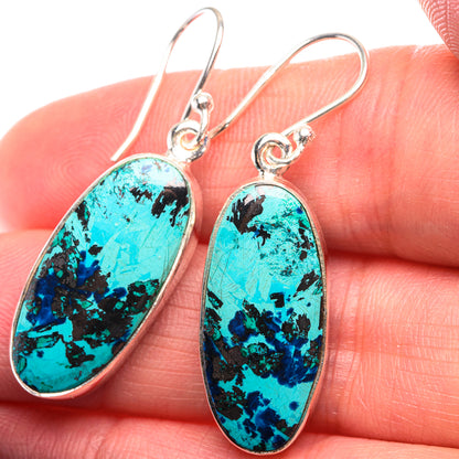Shattuckite oval drop earrings in 925 sterling silver with turquoise stone, close-up on hand