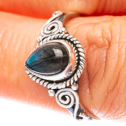 Sterling silver labradorite ring on finger; oval blue-green cabochon in braided border