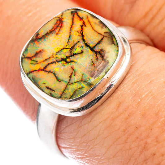 Oval green-and-gold opal cabochon in a sterling silver bezel ring