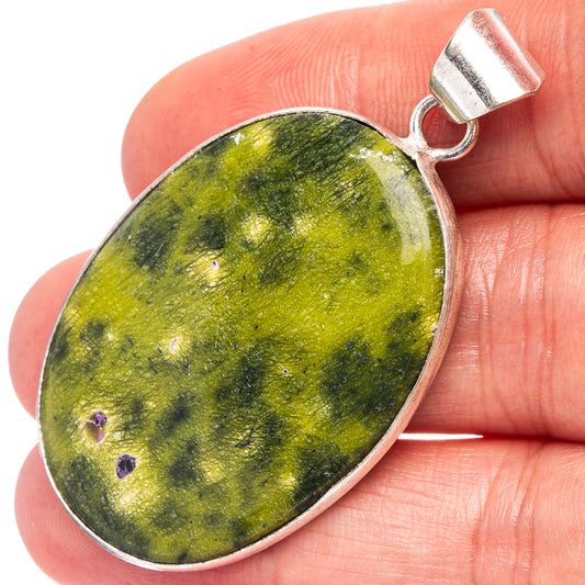 Oval green gemstone pendant with silver-plated bezel and loop bail on top.