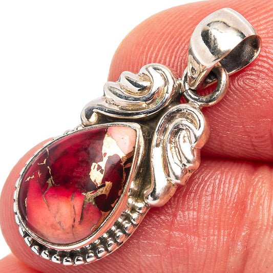 Sterling silver oval red gemstone pendant on finger close-up, decorative halo
