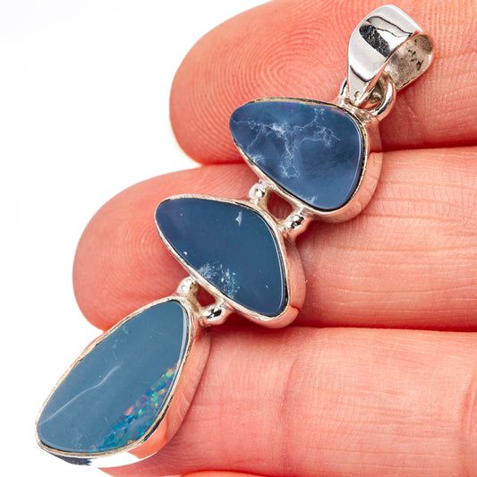 Sterling silver opal pendant with three blue teardrop doublets, close-up on hand