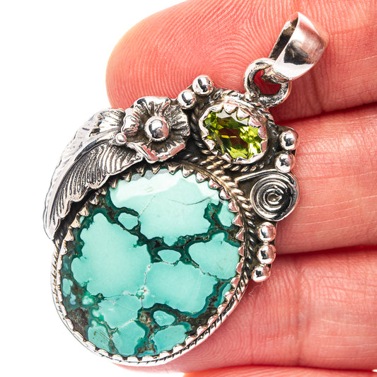 Sterling silver turquoise teardrop pendant with green center stone and ornate frame.