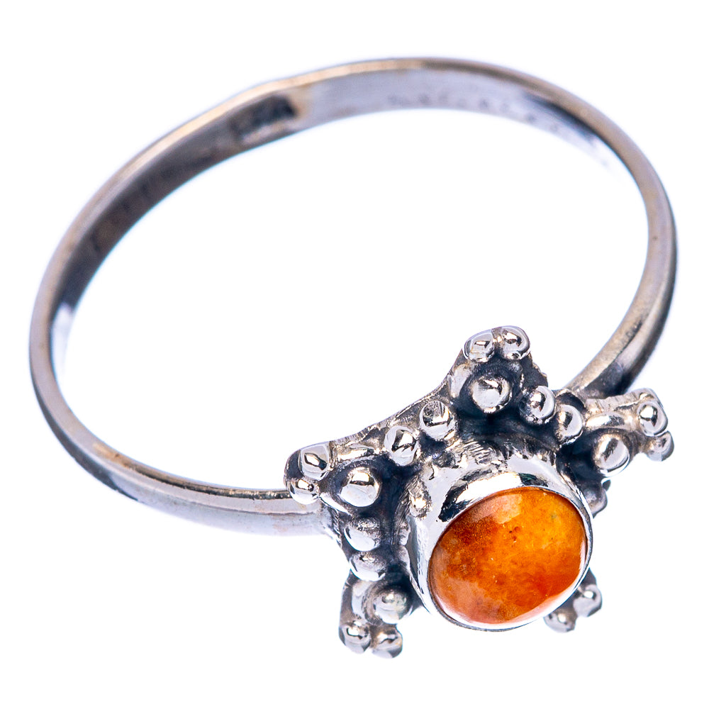 Silver ring with ornate leaf-like setting and orange cabochon, side view