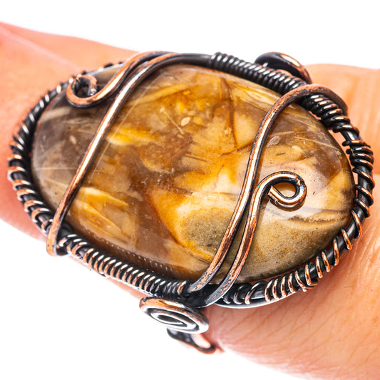 Oxidized copper wire wrap ring with oval amber-brown stone and swirl bezel