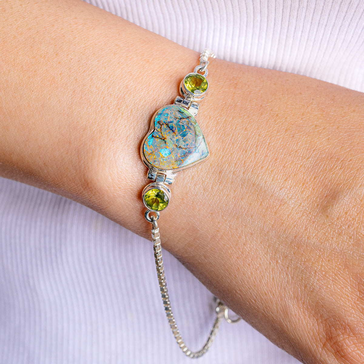 Sterling silver bracelet with heart-shaped opal pendant and round green gemstones