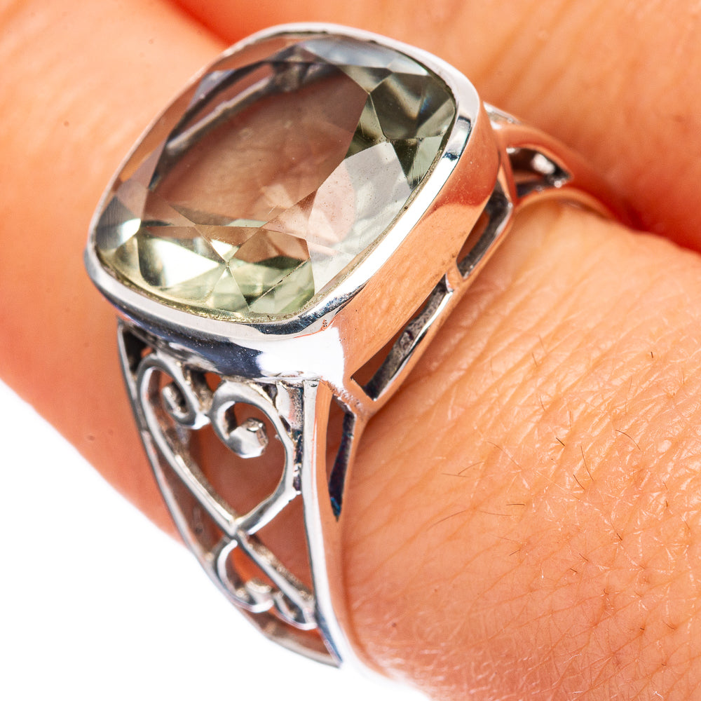 Sterling silver ring on finger, oval green faceted stone with decorative side scrollwork