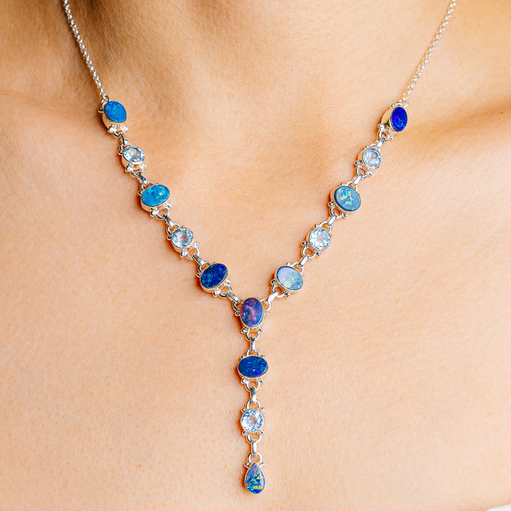 Sterling silver tennis necklace with oval blue topaz and small bezel-set stones, drop pendant