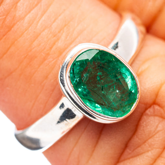 Silver ring with oval green emerald gemstone, close-up setting detail
