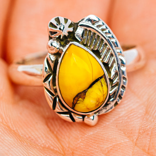 Sterling silver ring with oval yellow gemstone and decorative carved side setting
