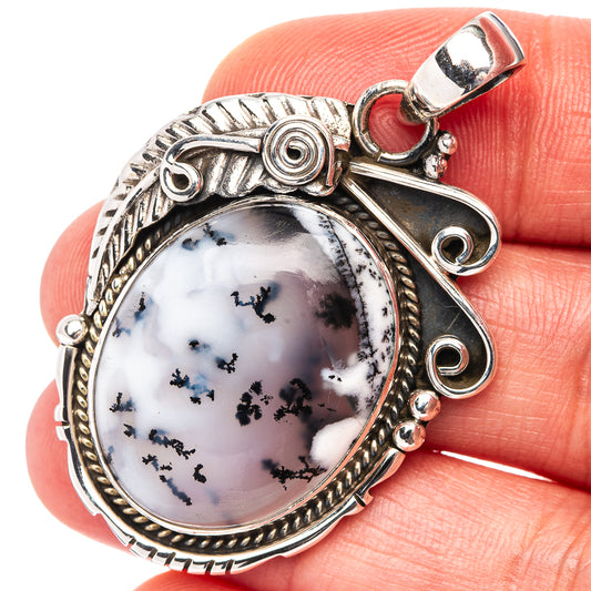 Sterling silver oval dendrite opal pendant with ornate frame and loop bail.