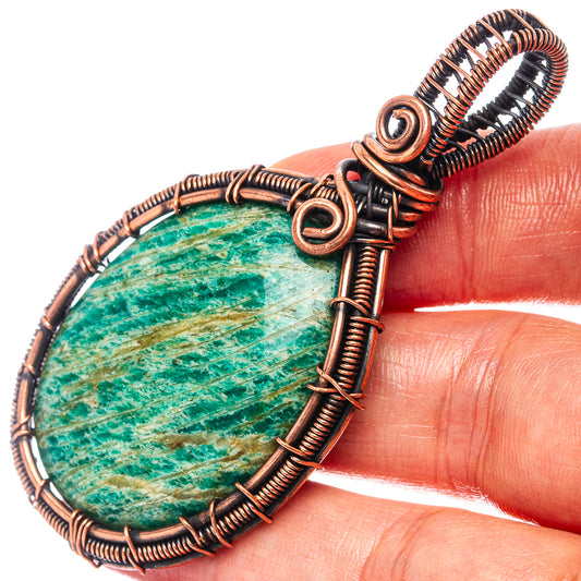 Oval teal amazonite pendant with oxidized copper wire coils and spiral bail, close-up