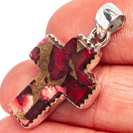 Cross pendant detail with red stone, gold flecks, and silver bail