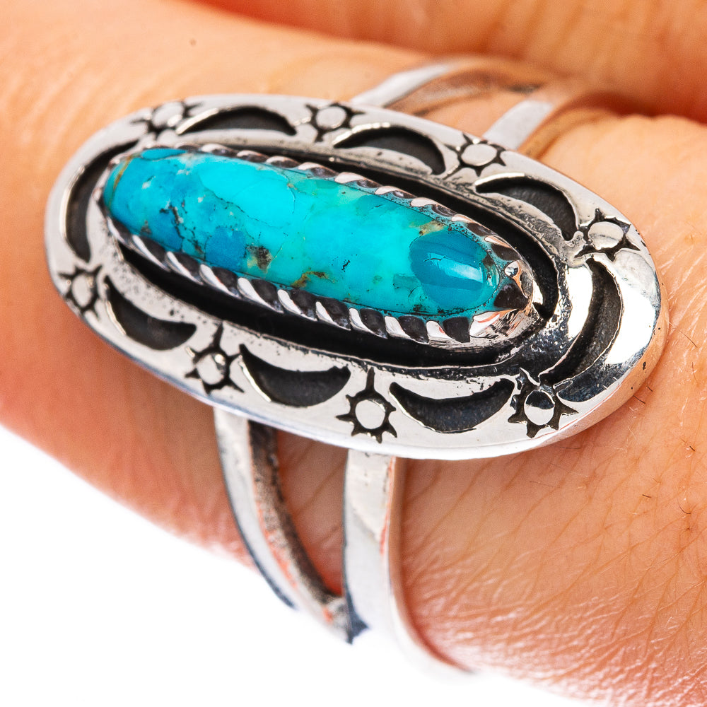 Oval turquoise cabochon sterling silver ring with ornate floral cutouts and black accents