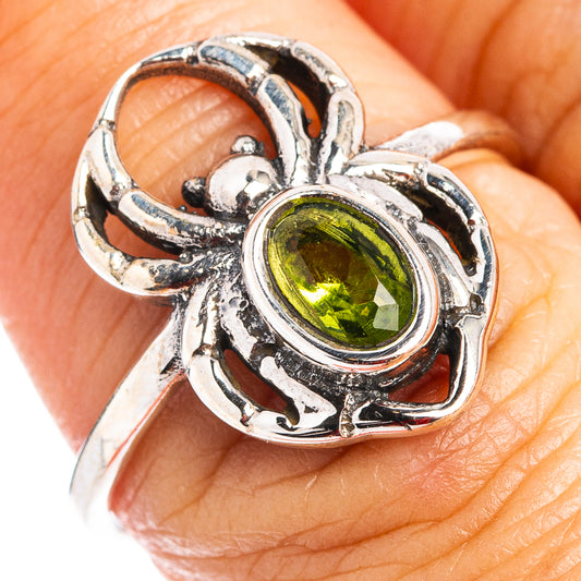 Sterling silver spider dainty ring with oval peridot-green gemstone, detailed webwork setting.
