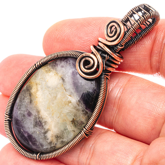 Wire-wrapped teardrop pendant with amethyst and copper spiral frame, close-up