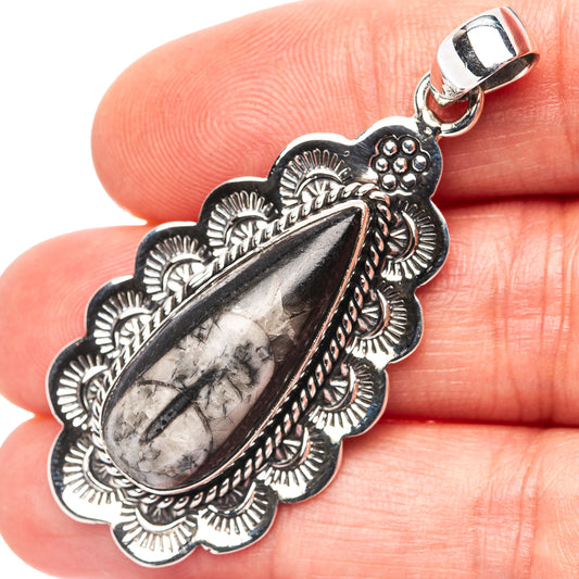 Silver fossil pendant with oval teardrop stone and ornate scalloped setting, bail top
