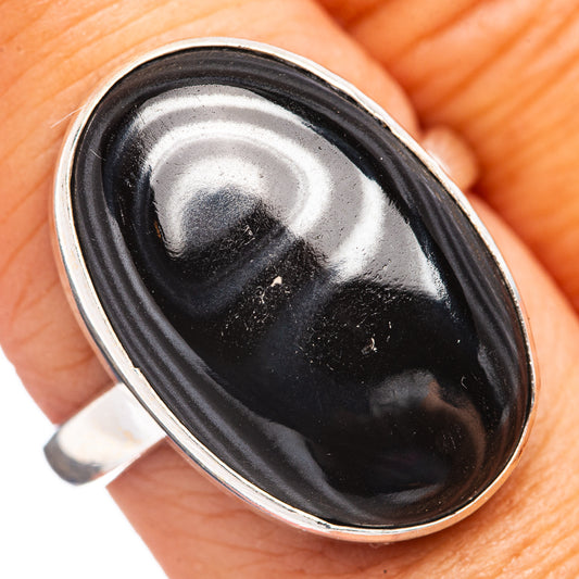 Oval black gemstone ring with .925 sterling silver bezel, close-up on finger