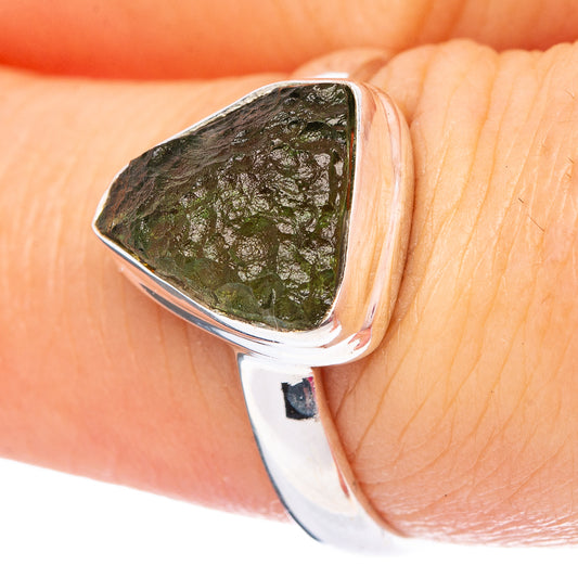 Sterling silver ring with triangular green moldavite stone on a finger