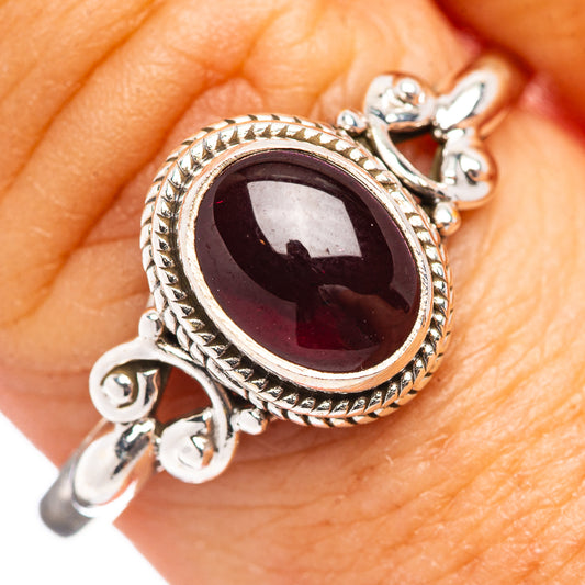 Garnet oval ring with ornate rope-edge halo and dark red gemstone on sterling silver band