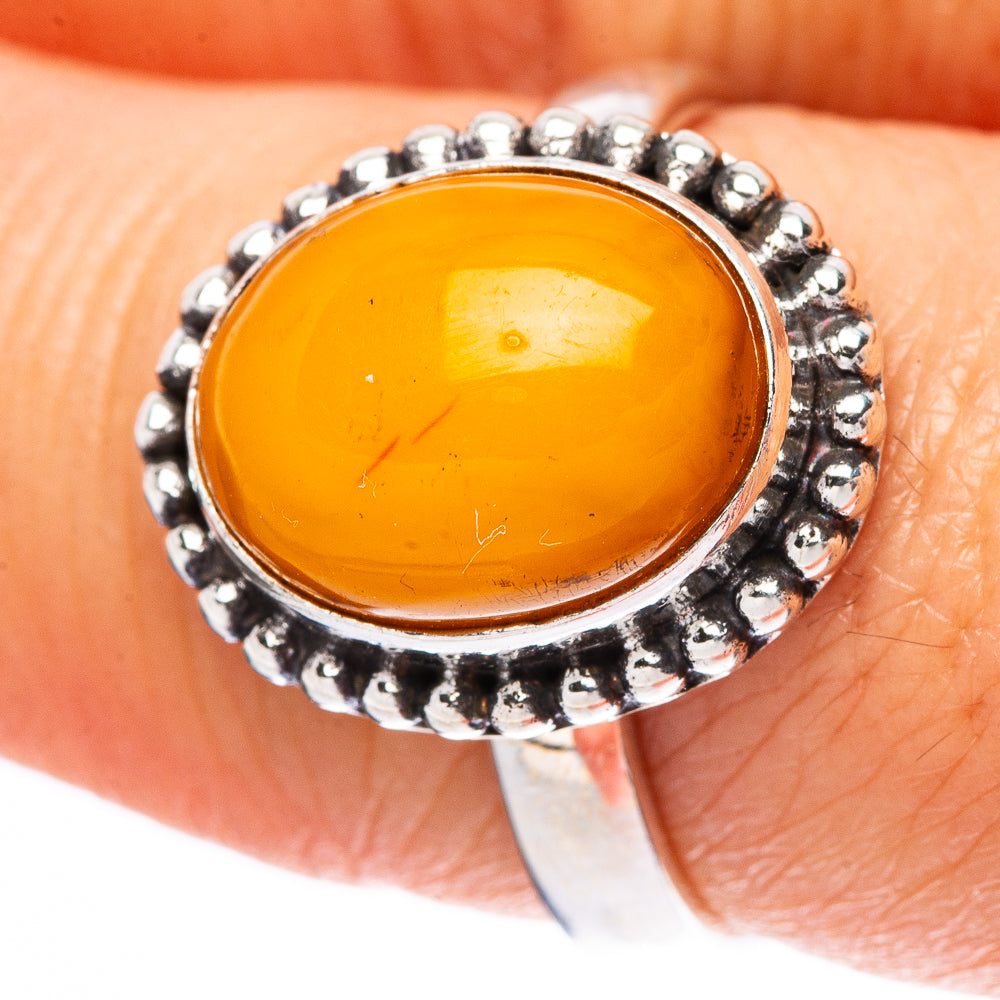 Sterling silver ring with oval amber cabochon and textured bead halo, close-up