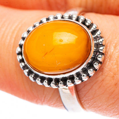 Sterling silver ring with oval amber cabochon and textured bead halo, close-up