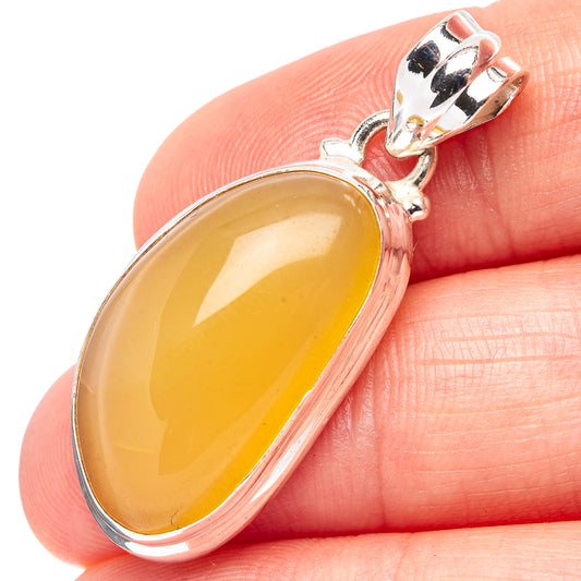 Oval amber pendant close-up on hand, yellow cabochon in .925 sterling silver frame.