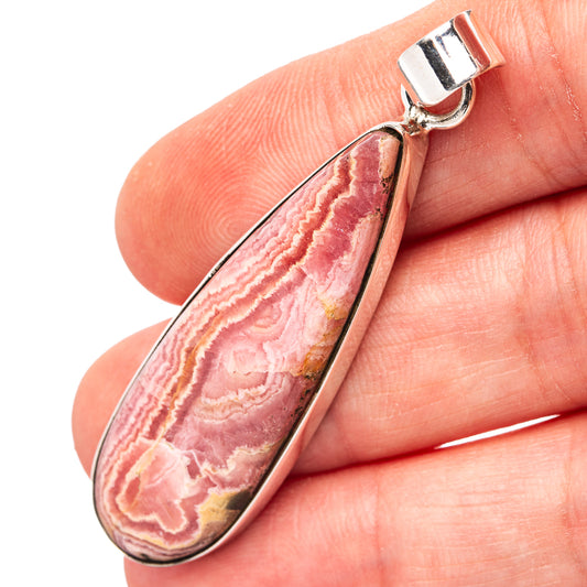 Rhodochrosite teardrop pendant in silver bezel, shown resting on fingertip