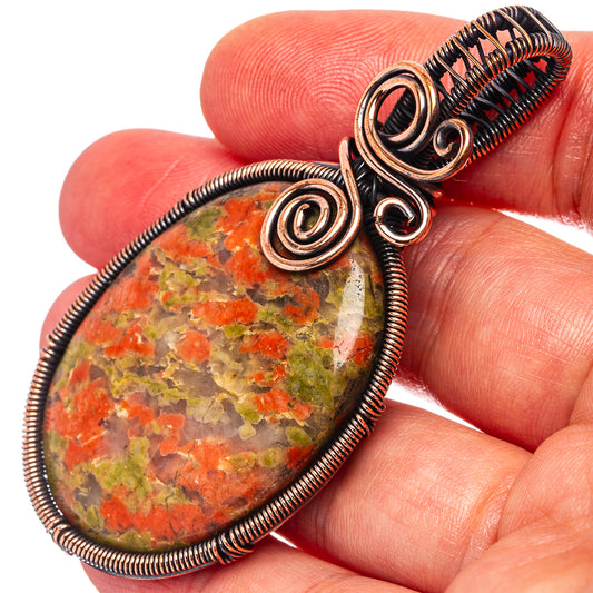 Unakite wire-wrap pendant close-up with oval multicolor stone cabochon and copper loops