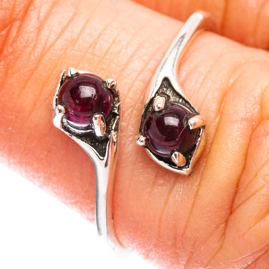 Sterling silver garnet ring on finger, oval deep red gemstone in V-shaped prong setting