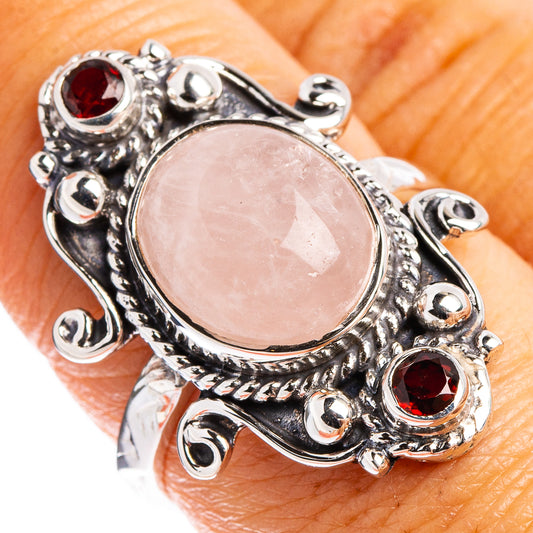 Rose quartz oval cabochon sterling silver ring with red garnet stones on hand