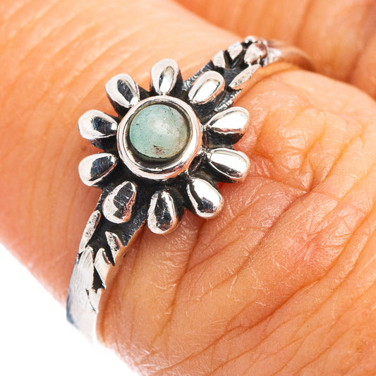 Sterling silver flower ring on finger with round green center stone