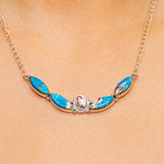 Sterling silver necklace with oval blue gemstone stations and central round halo charm
