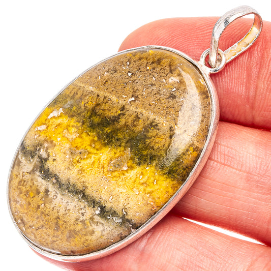 Silver-plated oval bumblebee jasper pendant held in hand, yellow and gray patterns