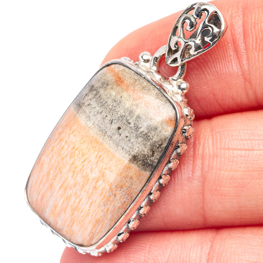 Rectangular sterling silver pendant close-up with orange and gray cabochon stone
