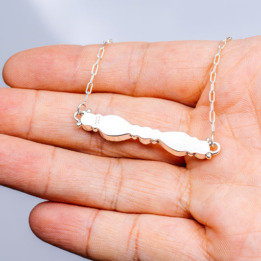 Turquoise and white stone necklace pendant on silver chain, side view