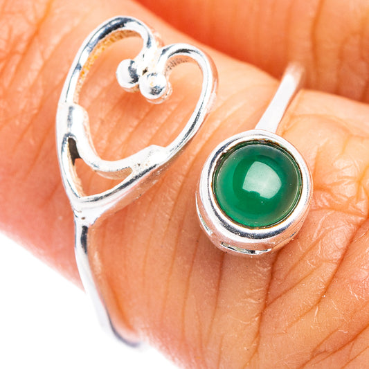Heart-shaped sterling silver ring with green cabochon stone on finger