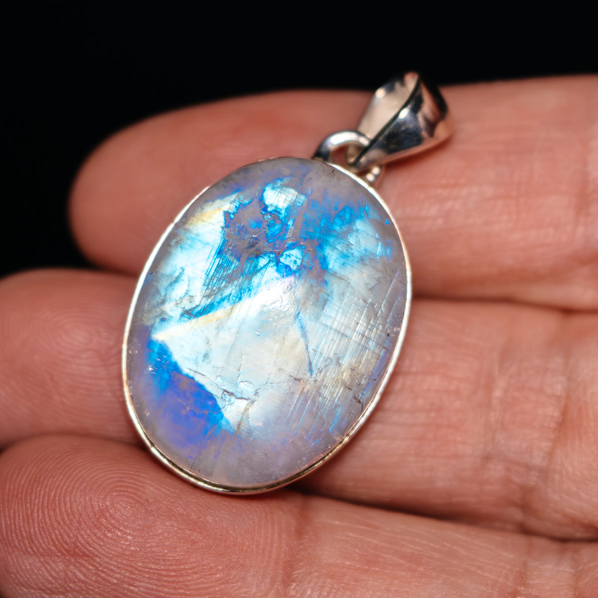 Oval rainbow moonstone pendant in .925 sterling silver setting with hinged bail