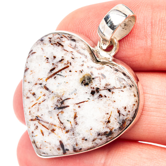 Heart-shaped sterling silver pendant with white stone, dark streaks, and loop bail