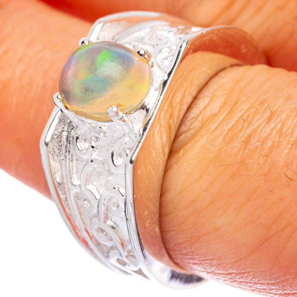 Sterling silver opal ring on finger, oval iridescent stone set in engraved band