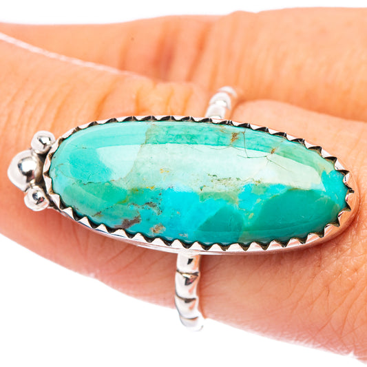 Sterling silver turquoise ring on finger, oval turquoise cabochon with serrated bezel