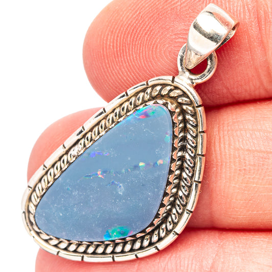 Sterling silver teardrop opal pendant with blue gemstone and ornate rope border.
