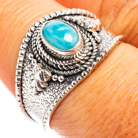 Ornate sterling silver ring with oval turquoise-blue cabochon and detailed side filigree