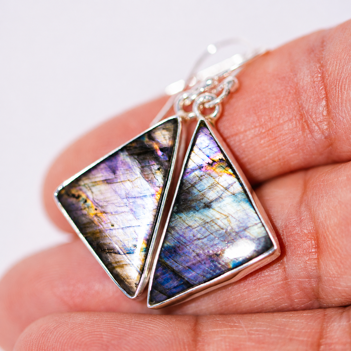 Sterling silver earrings with iridescent blue triangular stones in a drop setting