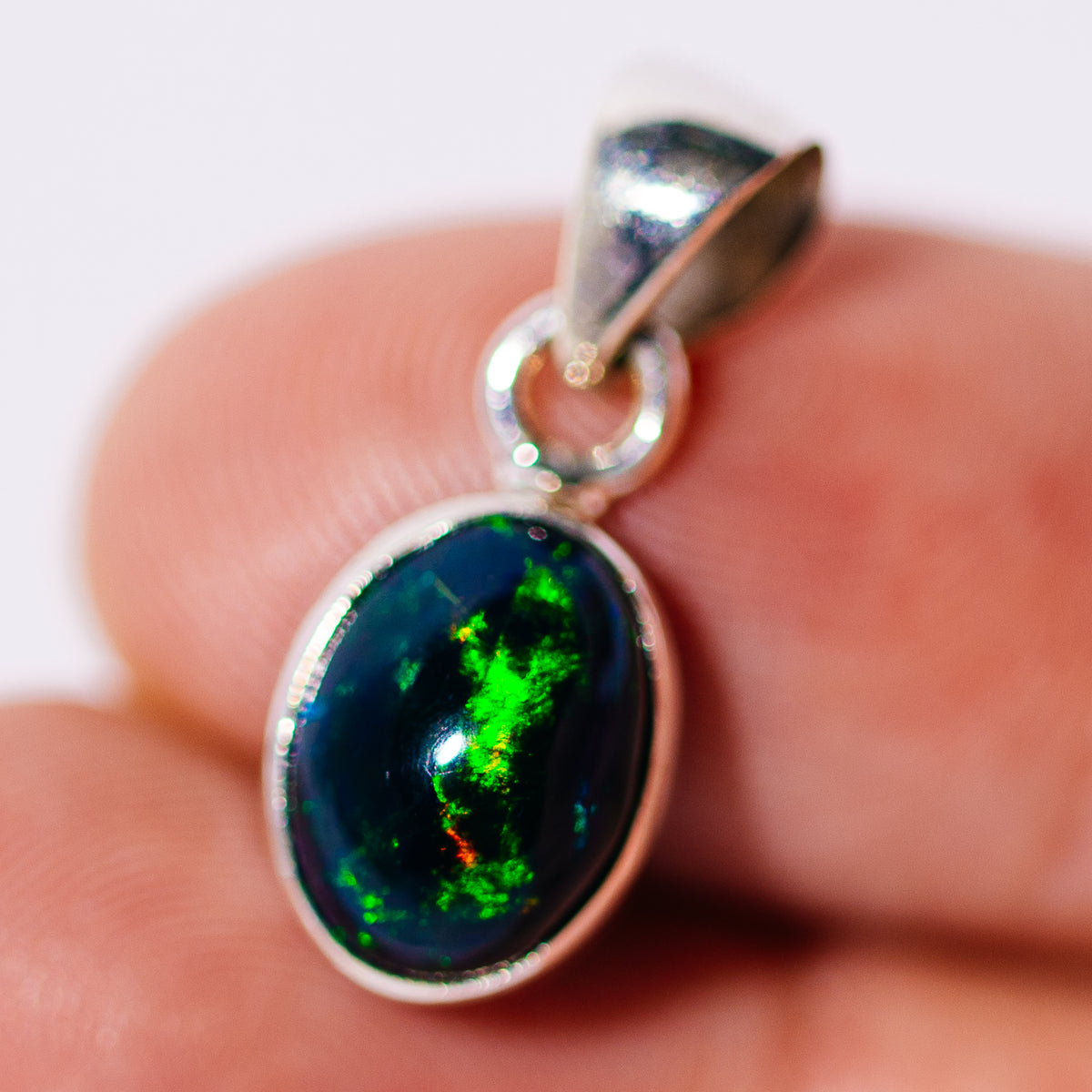 Black Ethiopian opal pendant in a sterling silver setting, oval stone with vivid green flashes