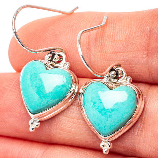 Turquoise heart earrings with .925 sterling silver hooks and ornate bezel, close-up on stones.