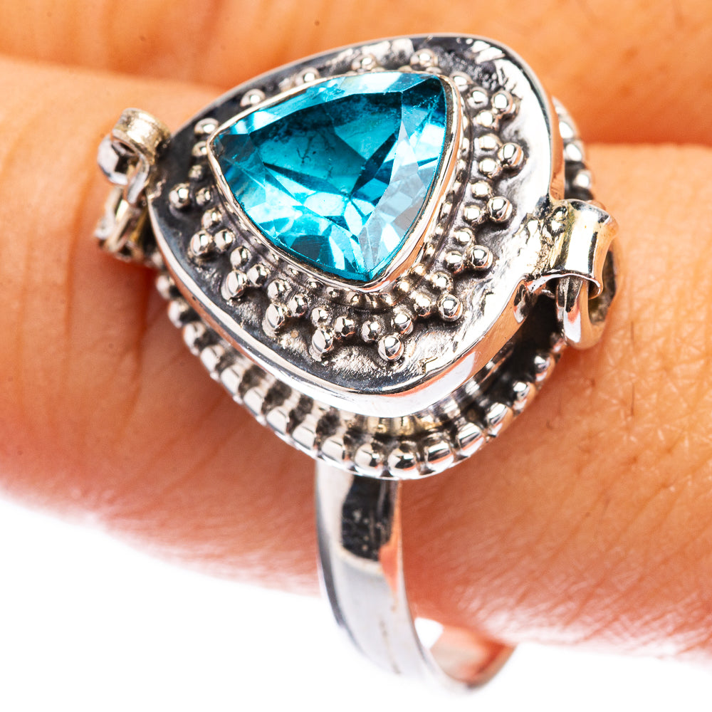 Silver ring with oval blue gemstone, ornate bezel and halo prongs