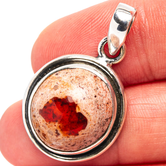 Sterling silver round fire opal pendant held in finger, red cabochon bezel setting