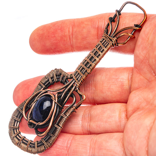 Sodalite gemstone wire wrap pendant detail on oxidized copper frame, oval blue cabochon